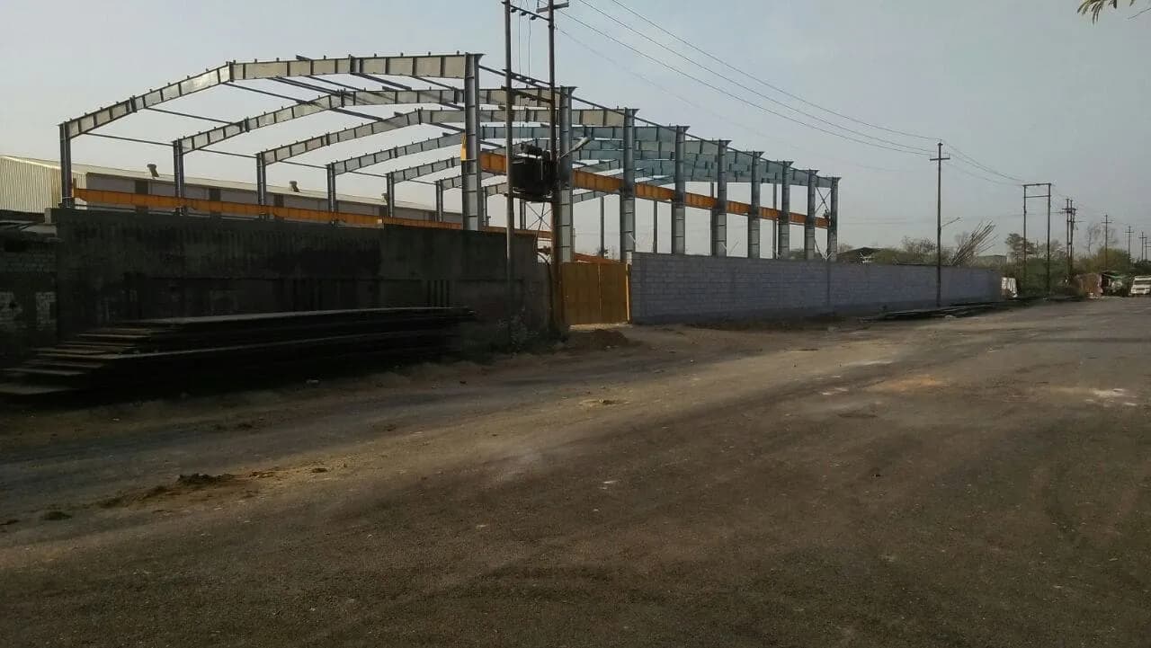 Erected steel building frame beside a fabrication yard